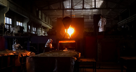 Smelting metal in a metallurgical plant. Liquid iron from metal ladle pouring in castings at factory