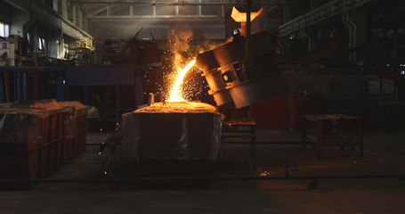 Smelting metal in a metallurgical plant. Liquid iron from metal ladle pouring in castings at factory