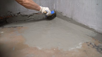 Industrial worker on construction site laying sealant for waterproofing cement. Worker apply liquid foil to the terrace. Workers applying a memory shape polymer waterproofing. 