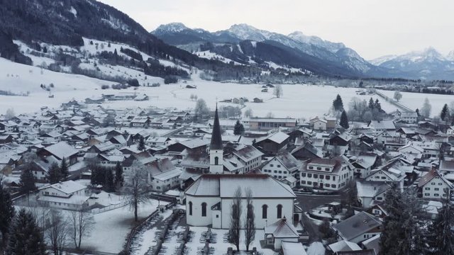 Aerial view of the small cozy german town at the mountain bottom at sunrise in a winter season, Halblech city, Germany, Bavaria, Branches of trees are covered with hoarfrost, sunny weather