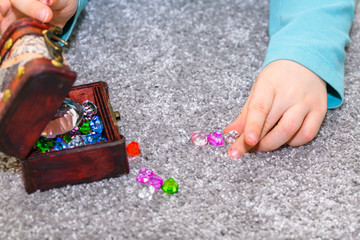 Five year old boy with a treasure chest lining up multicolored gems