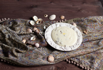 Obraz na płótnie Canvas Semolina with raisins in white plate with shells on table cloth on brown wooden background