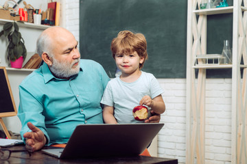 Kid with old teacher learning in class on background of blackboard. Old and Young. Teacher is skilled leader. Student and tutoring education concept. Grandfather and grandson.