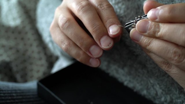 slow motion the woman is cutting her nails with small scissors by herself 