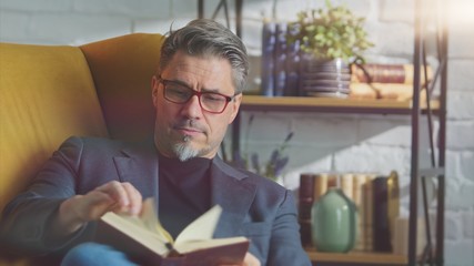 Older white man in glasses reading at home