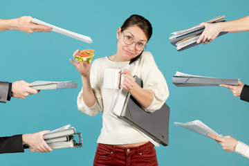smiling office employee holds the phone with her shoulder, drinks coffee, eats
