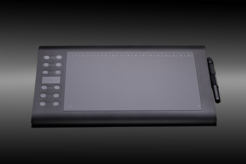 Digital graphic tablet with pen on a black background