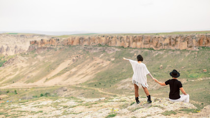 Hipster couple hiking in mountains landscape, banner panorama. Woman and man point the finger on something. Looking at view happy enjoying healthy outdoor lifestyle. Grand Canyon National Park USA