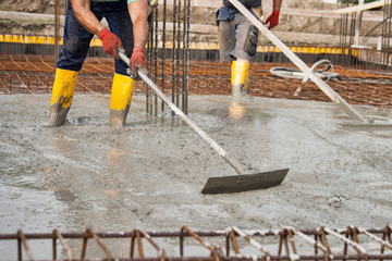 bricklayers who level the freshly poured concrete to lay the foundations of a building.
