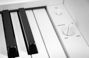 master volume control on piano and button on and off on device, white piano and keys, gray color...