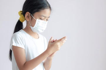 The child girl is rubbing her hands with alcohol gel on her palm to clean