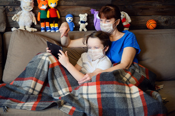 Photo in the home interior mom cares for a boy of 9 years old, sitting next to quarantine on the couch