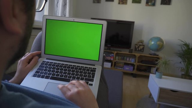 Young Caucasian Male Swiping On His Laptop Working From Home, Green Screen