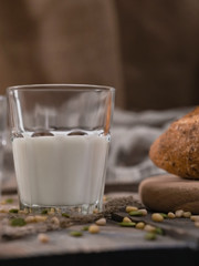 Glass of milk for breakfast in the country on World Milk Day. Scattered seeds and nuts on wooden table.