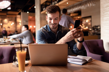 Young man sitting at cafe and working on laptop.