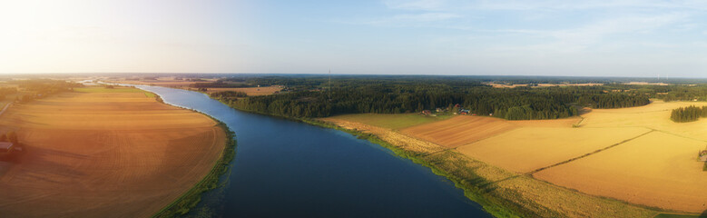 Rural aerial view of agriculture fields, meadows and beautiful river at sunset in Finland. View of...