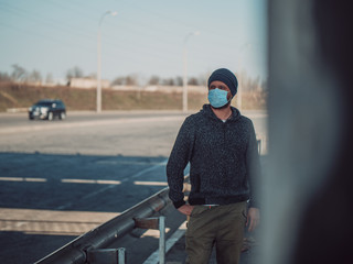 Hipster Man In A Medical Mask For Protection Against Flu Virus Or Coronavirus Outdoor Againts Highway. Corona Virus Pandemic. Epidemic Viral Respiratory Syndrome. 2019-nCoV. High Quality Photo