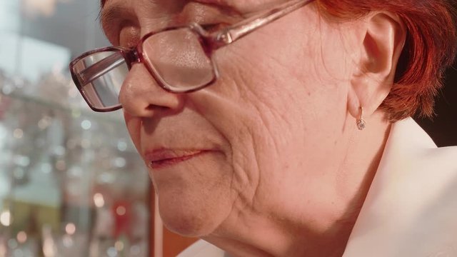 Close up view and low angle view of old woman face. Lady licks stamp to stik it. Side view.