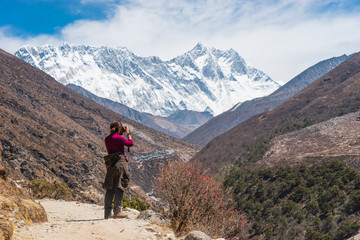 A woman taking picture while trekking in Everest Base Camp, Himalaya mountain range in Nepal
