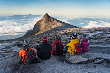 Trekkers sitting on rock looking to South peak, Kinabalu national park in Borneo island, Sabah state in Malaysia - obrazy, fototapety, plakaty