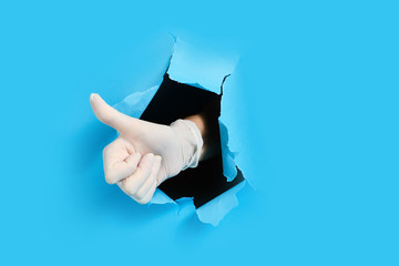 Hand in glove shows like through hole in paper. isolated on a blue background.