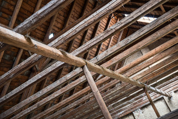 Aged beams in an old barn. Old roof achitecture detail. Wooden timbers.