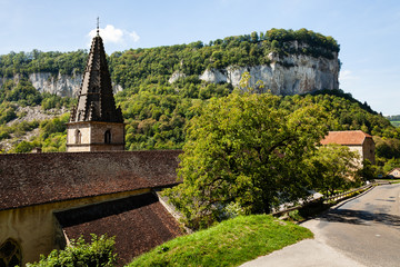 Old church in valley in Baume les Messieurs village. Green plants vegetation around. Mountain in...