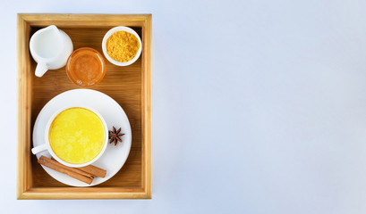 Golden milk, turmeric, honey, cinnamon and star anise on a wooden tray on a grey background. Masala Haldi Doodh