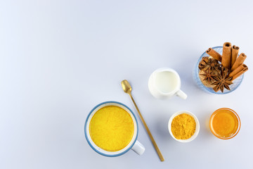 Golden milk, turmeric, honey, ginger root, cinnamon and star anise on a grey background.