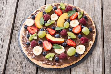 Fototapeta na wymiar Fruit pizza with nut nougat cream , fruit and berries