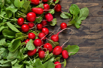 Fresh, young radish on a wooden background with space under the text. Top view.