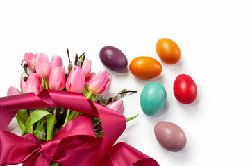 Easter background with colorful Easter eggs and a bouquet of tulips and catkins tied with a ribbon