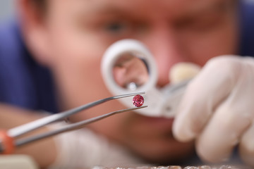 Male looks through magnifying glass brink diamond. Man checks safety product and stone, cleans and...