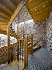Modrrn loft interior of entrance in multi-storey apartment building. Brick wall. Wooden staircase.