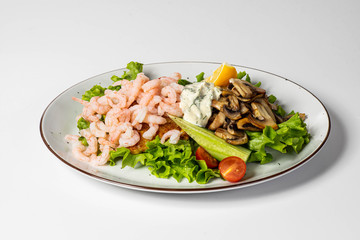 Tasty dinner. Delicious food on the white plate isolated on white. Prawns and fried mushrooms. Close-up.