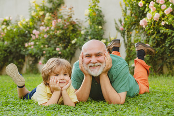 Naklejka na ściany i meble Happy child with Grandfather playing outdoors. Grandfather with Son and Grandson having Fun in Park. Happy grandfather and grandson relaxing together. Grandfather and son.