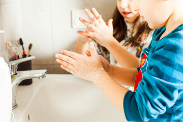 Boy and girl washing their hands with soap