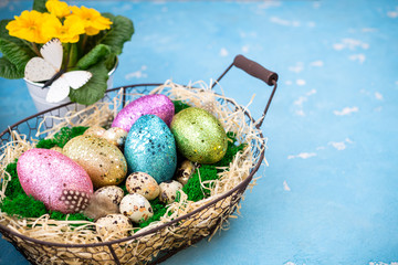 Spring Easter background for holiday. Easter composition with colorful Easter eggs on moss in basket and spring flower pot. Top view
