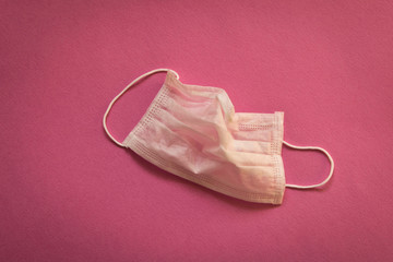 CORONAVIRUS. A crumpled medical mask on a pink background. Concept of protection against coronavirus.