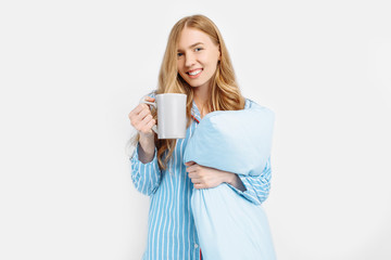 Beautiful girl in striped pajamas, with a Cup in her hands , drinking coffee or tea in the early morning