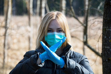 Woman in protective sterile medical mask on her face looking at camera outdoors