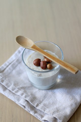 Glass of vanilla pudding with hazelnut topping and wooden spoon. Selective focus.