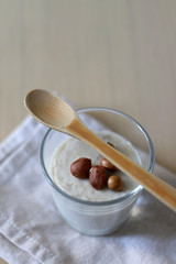 Glass of vanilla pudding with hazelnut topping and wooden spoon. Selective focus.