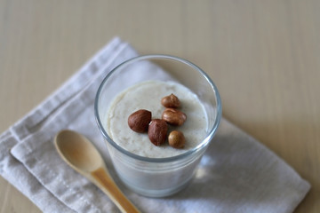 Glass of vanilla pudding with hazelnut topping and wooden spoon. Selective focus.