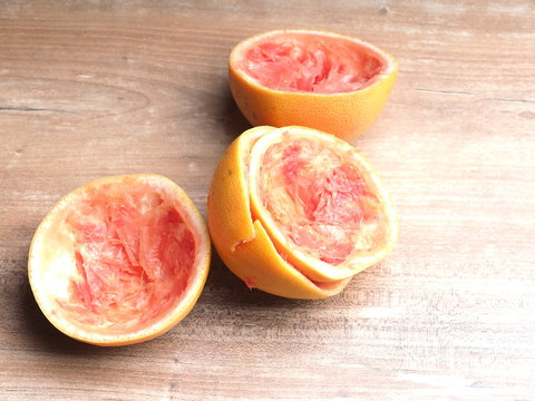 Half Of Squeezed Pink Grapefruit On Wood Background