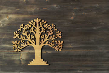 Laser cut wood tree ornament on wooden background.  Wooden tree symbol on wood texture with copy space..