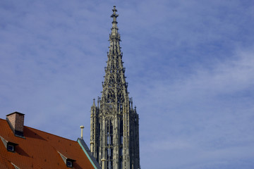 Fototapeta na wymiar Steeple of Minster of ulm with the view of the historic house roof with copy space, gothic church steeple of cathedral of ulm in germany