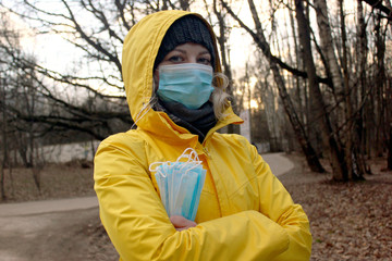 Young woman with medical mask on her face and a pack of masks in her hand during coronavirus pandemic
