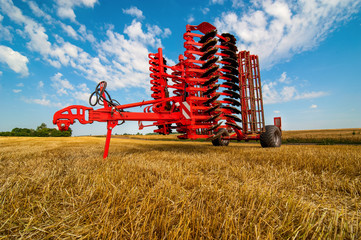 Red harrow folded for transportation for cultivating the land. Harrow on the field and beautiful...