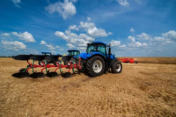 Foto op Aluminium new blue tractor in motion working with plow. © pavlobaliukh